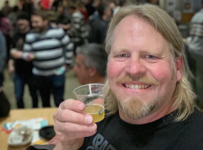 man holds up beer cup