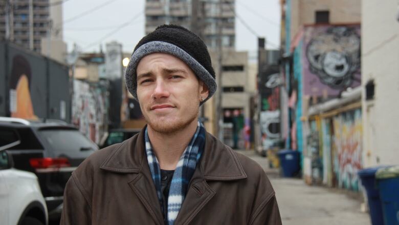 Man stands in an Windsor alley covered in graffiti art