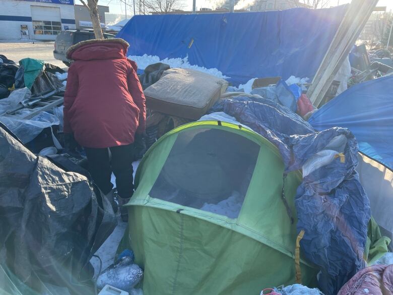 A person walks among tents and snow