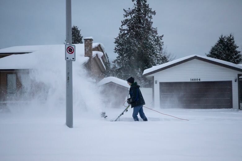 A man clears his sidewalk with a snow blower after a heavy snowfall in Surrey, B.C..