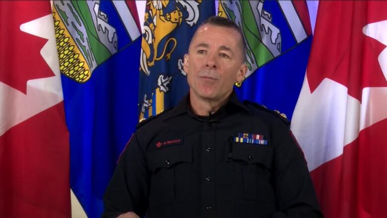 Calgary's police chief sits in front of a wall of flags as he talks about policing in 2022 as part of a year-end interview with CBC News.