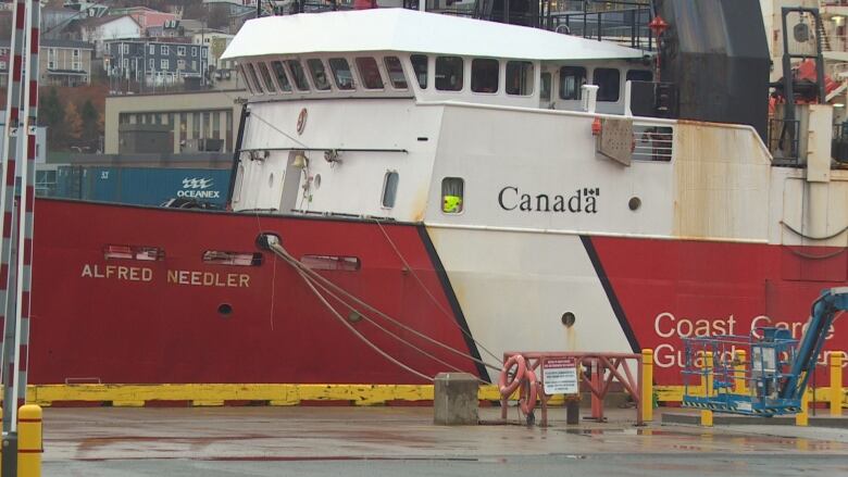 A red and white Coast Guard ship is tied to a dock.