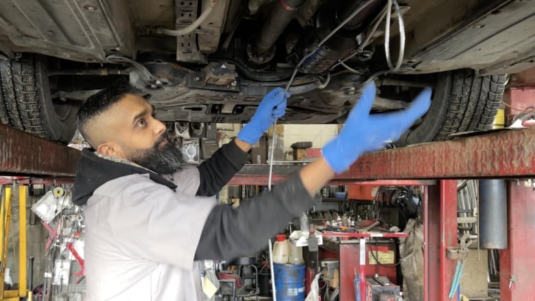 Ravi Chandra, is pictured under a vehicle. He is installing a wire device that could help prevent thieves from stealing the car's catalytic converter.