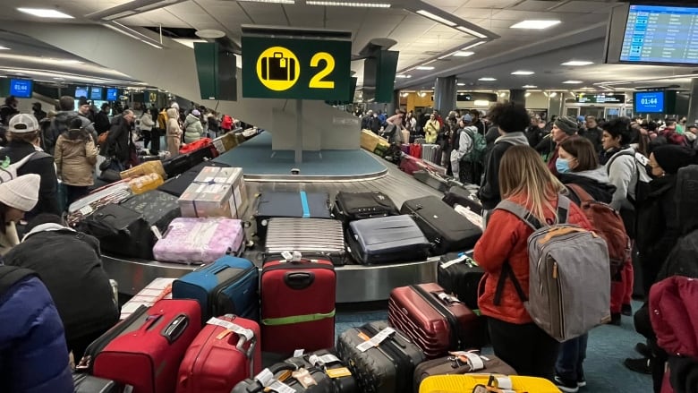 A mess of colourful luggage and frustrated passengers is pictured at a crowded baggage terminal inside Vancouver International Airport.