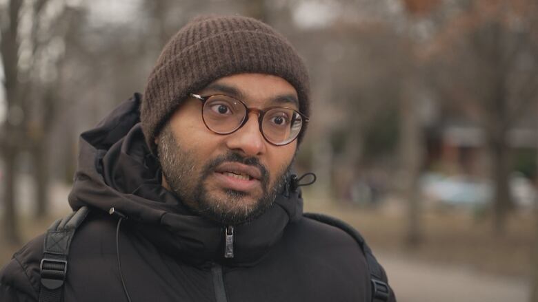 A close-up photo of Syed Hussan, who stands outside, wearing a toque and black winter jacket.