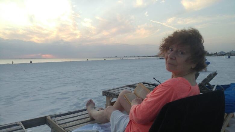 A woman smiles on a beach. 