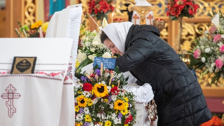 A woman leans over a casket.