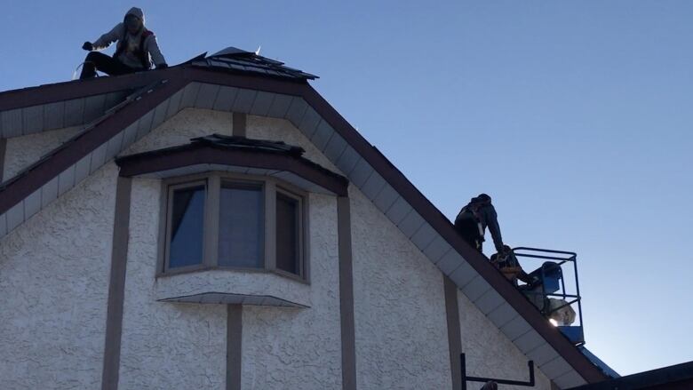 Workers are seen on the roof of a house in Red Deer, Alta. They are installing a new roof. 