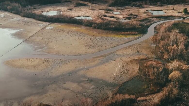 An aerial image shows water receding from a muddy field. In the top right corner there is a creek. 