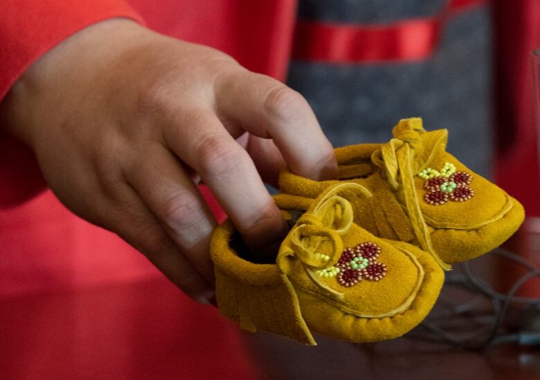 A pair of childrens moccasins represents the tens of thousands of First Nations children who are forcibly removed from their homes, communities and families.