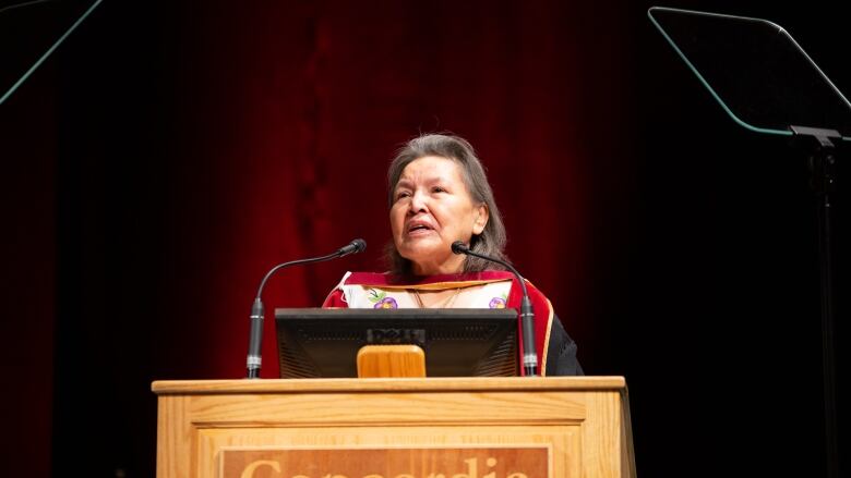 Woman in ceremonial clothing at a podium.