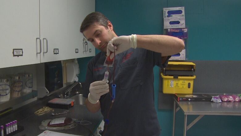 A man holds a bag of blood.