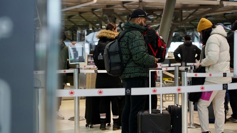 Travellers wait in line at an airport.