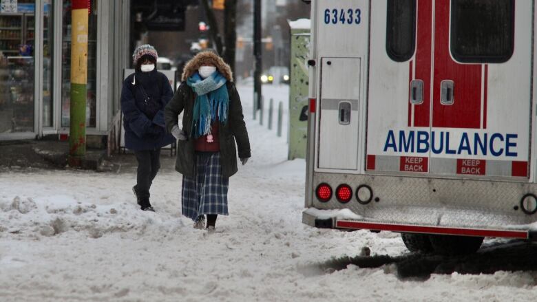 1...  Pedestrians walking past and ambulance call on Granville Street in downtown Vancouver during freezing rain. 2... A person seeking shelter from freezing rain outside of a restaurant on Granville street downtown Vancouver 3... Puralotor delivery van crossing Robson downtown Vancouver