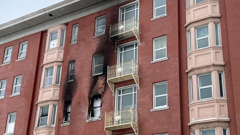 Smoke damage can be seen on the outside of a red brick building.