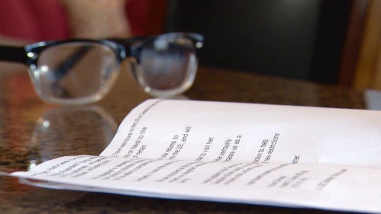 Reading glasses and a printed letter sit on a table.