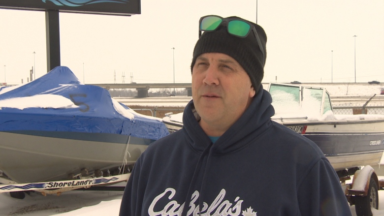 A man wearing a hoodie and with sunglasses on his hat speaks with a reporter. 