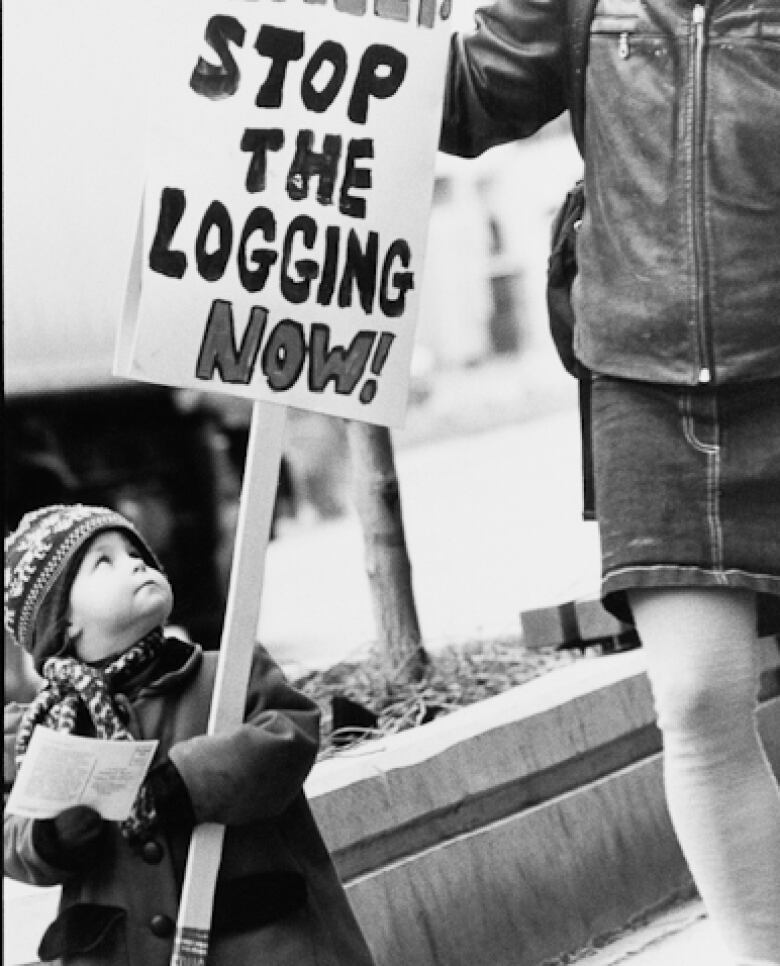 A young child holds up a sign that says 