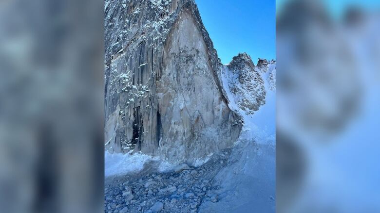 A side of a mountain peak is pictured with its side shaved off, and fragments of rock are visible in the snow.