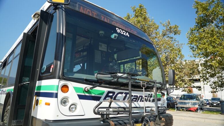 A bus marked 'B.C. Transit' with the top chyron reading 'NOT IN SERVICE' sits parked at a bus stop.