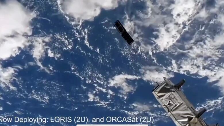 A rectangle-shaped satellite floats in space over planet Earth. 