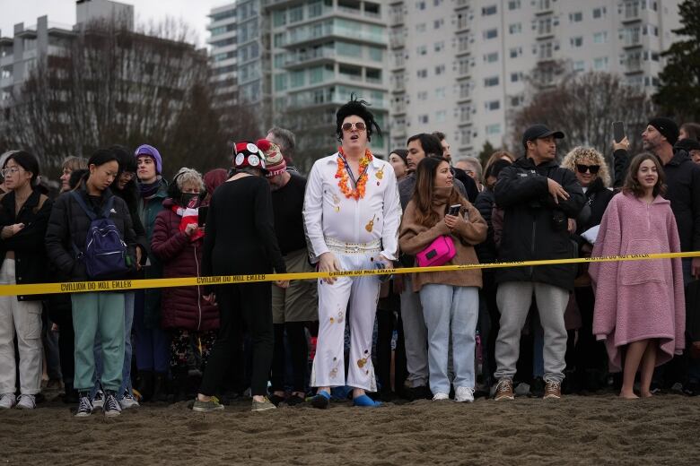 A person wearing an Elvis costume waits in line with others to take part in a Polar Bear Swim on New Year's Day.