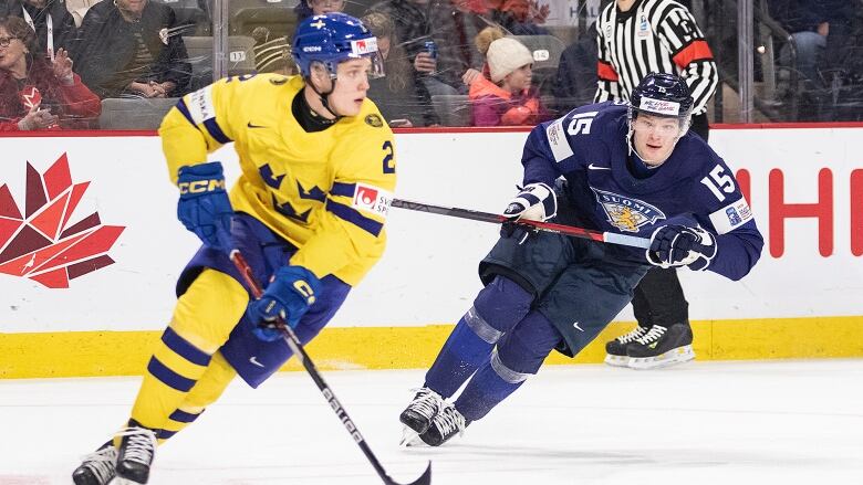 Swedish hockey player stick handles the puck away from his opponent, a Finnish hockey player in preparation to make a pass.