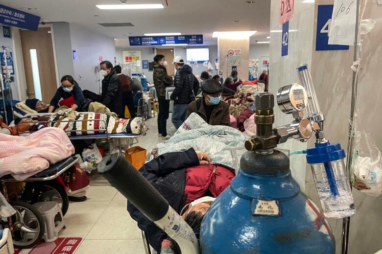 An oxygen tank and people on stretchers are shown in a hospital hallway.