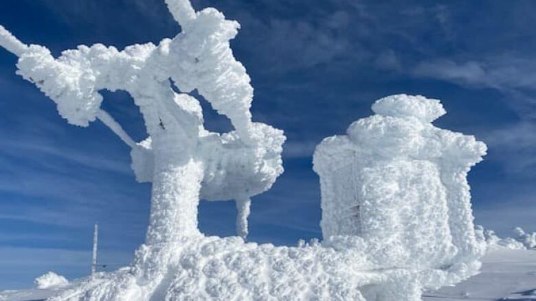 An alpine lift infrastructure encased in ice on a snowy slope.