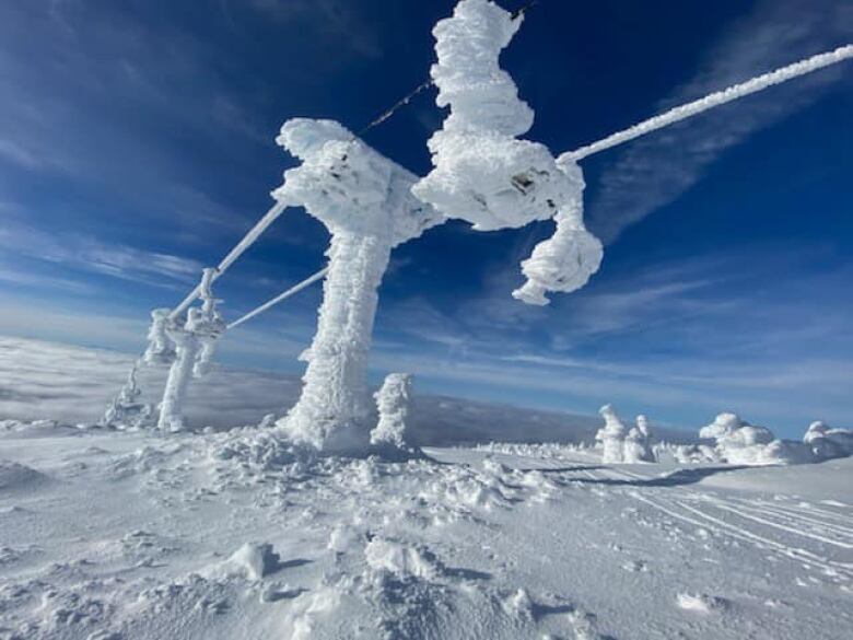 A chairlift encased in ice on a snowy slope.