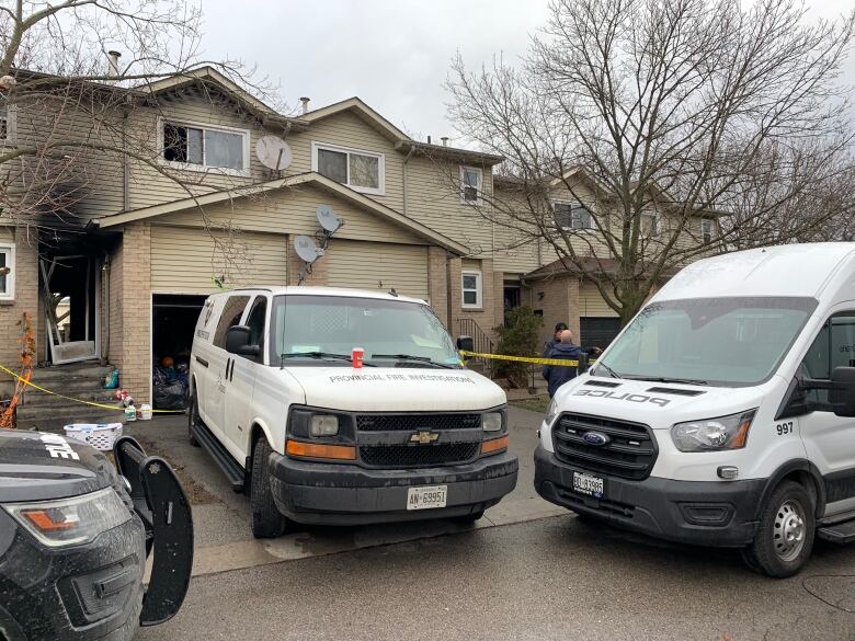 A townhouse with a missing door with a forensics van in front. 