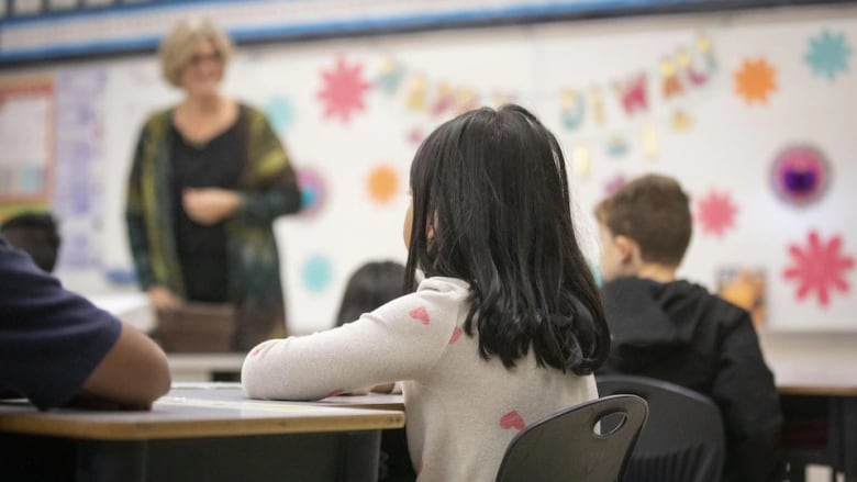 A child sits at a table in an elementary school classroom