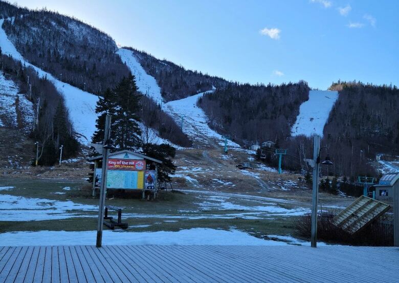 A photo of a ski hill. The top half of the mountain is largely covered in snow, but less snow appears the further you look down the mountain.