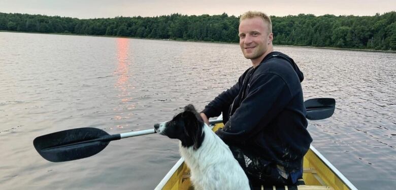 A man in a canoe with a dog. 