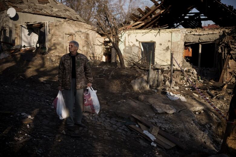 Anatolii Kaharlytskyi, 73, stands near his house, heavily damaged after a Russian attack in Kyiv, Ukraine, Monday, Jan. 2, 2023. Kaharlytskyi was injured and his daughter Iryna died in the attack on Dec. 31, 2022. (AP Photo/Renata Brito)