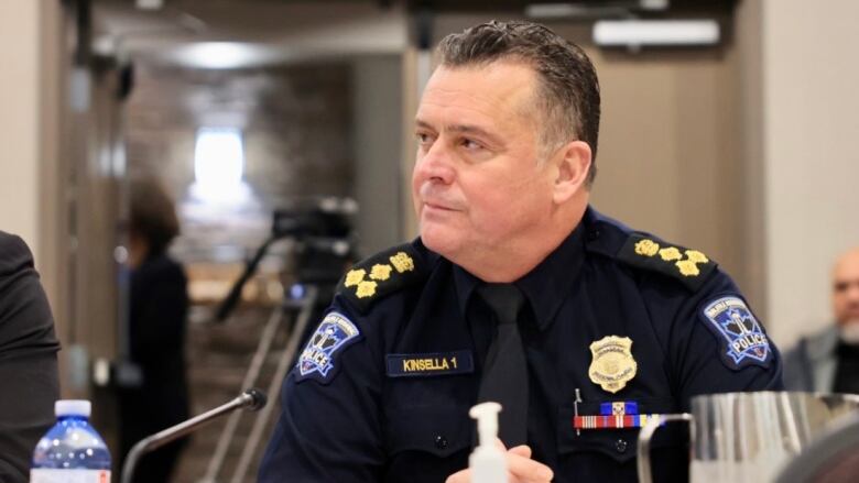 A male police chief sits at a table during a hearing. 