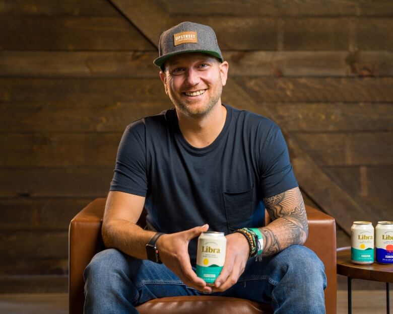 A photo Mitch Cobb holding a beer can, sitting on a chair. Cobb is the co-founder of non-alcoholic beer brand Libra, and the CEO of Upstreet Craft Brewing in P.E.I