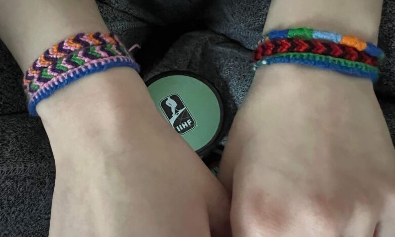 Two hands wrapped in colourful bracelets. 