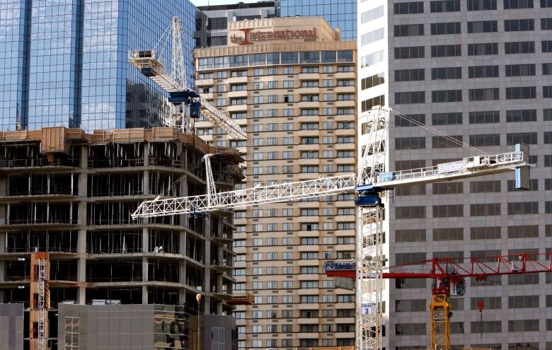 Multiple cranes are set up as a building is being constructed in downtown Calgary.