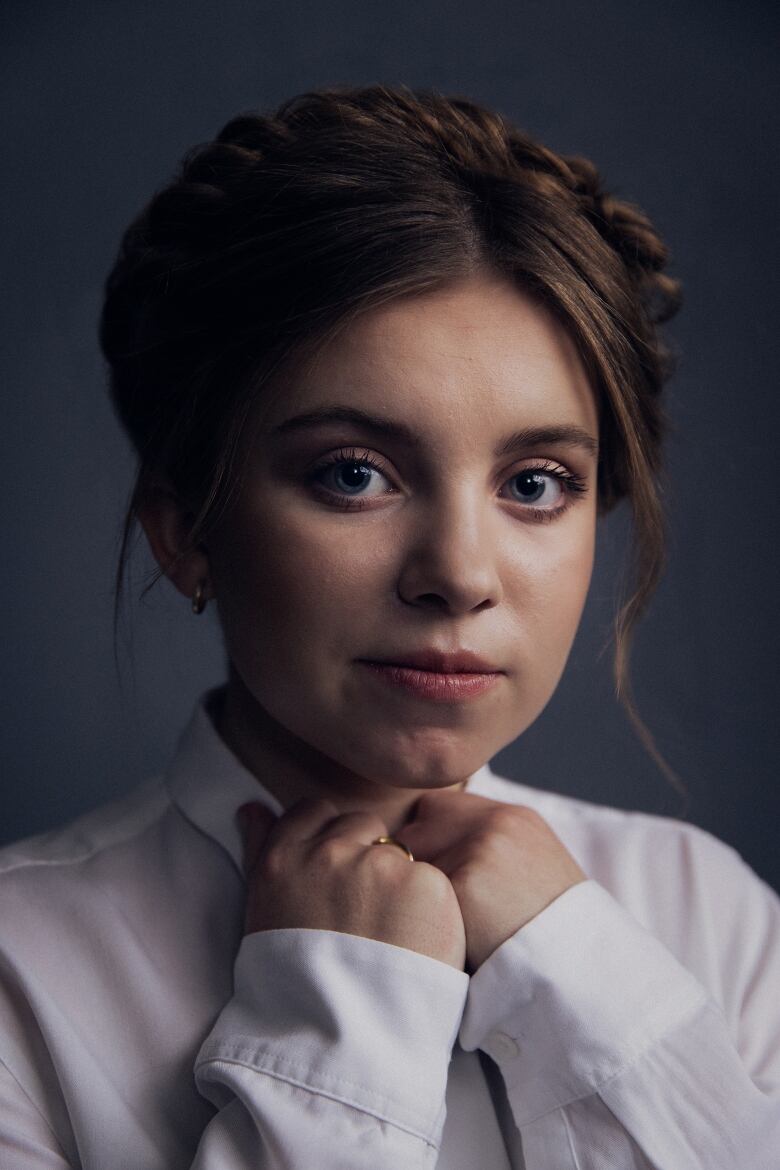 Closeup of Kate Hallett smiling as she cups her hands to her collar.