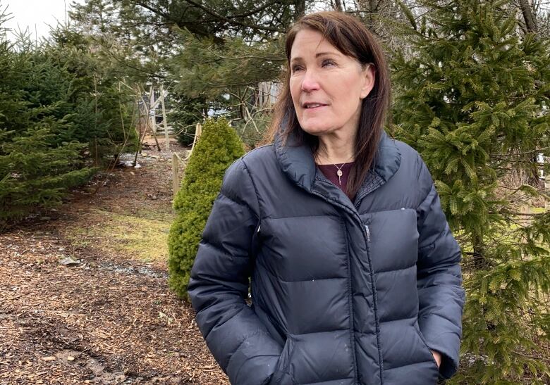 Woman in puffy coat stands in a forest clearing. 