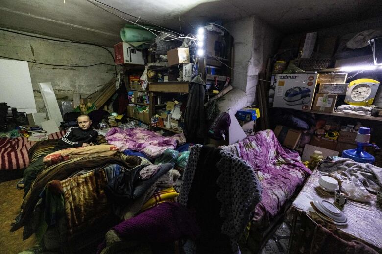 The part of the room that is visible is includes several places to sit. Shelves against the wall are packed with items, including a clock and a number of boxes.