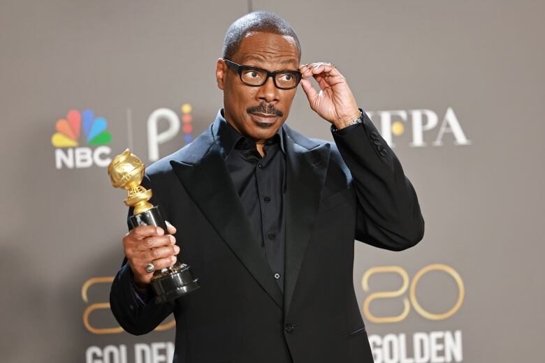 Man with award adjusts his glasses.