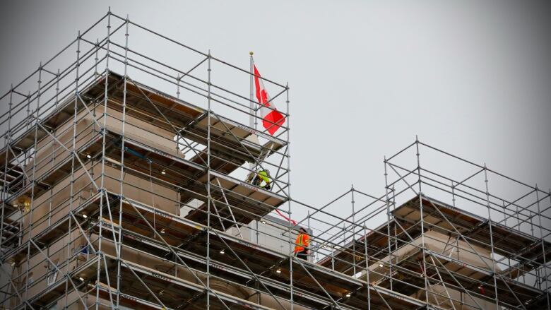 A mid-rise building covered with scaffolding with construction workers on the scaffolding.