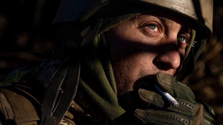 A man in closeup wears a green helmet. His face is partly in shadow.