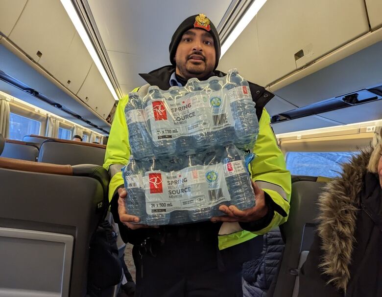 A paramedic carries bottled water down the aisle of a train car.