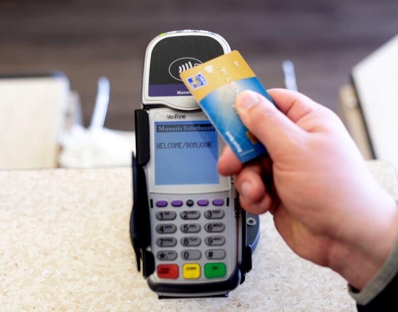 A person taps a bank card to tap on a reader.