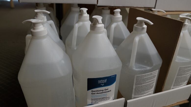 A close-up of a box filled with big jugs of hand sanitizer.