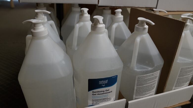 A close-up of a box filled with big jugs of hand sanitizer.