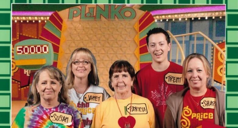 A group poses for the camera in front of a Plinko game.